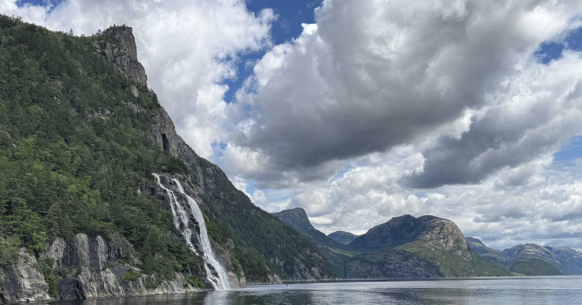 Meredek sziklafal, mély víz és vízesés Norvégiában